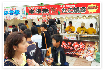 食べ物の屋台とその側を通るイベントの参加客